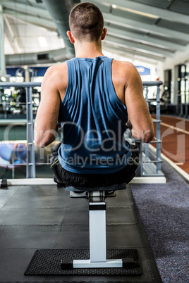Muscular man using rowing machine