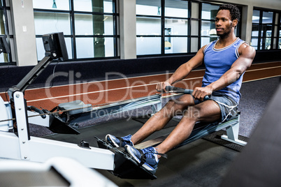 Muscular man using rowing machine