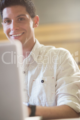 Smiling male student using laptop