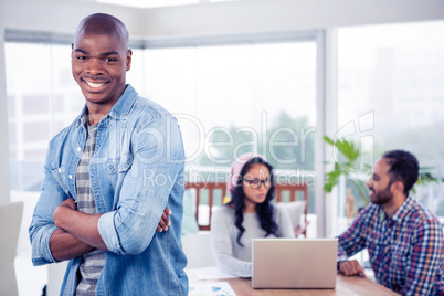 Portrait of smiling businessman standing with arms crossed in of