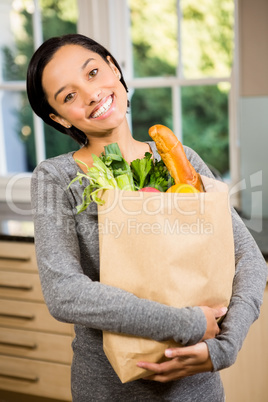 Smiling brunette holding grocery bag
