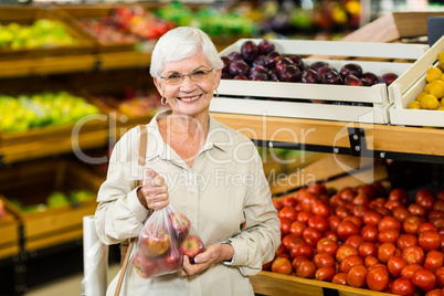 Senior woman holding bag with apple