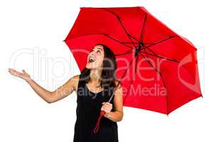 Shocked woman looking up while holding red umbrella