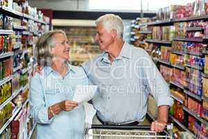 Smiling senior couple with cart and list