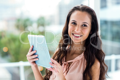 Happy woman using tablet looking at camera