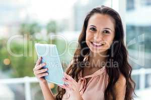 Happy woman using tablet looking at camera