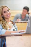 Smiling attractive student using laptop