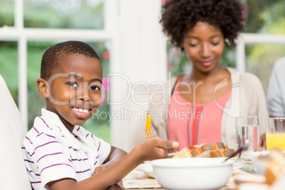 Smiling son eating his dinner