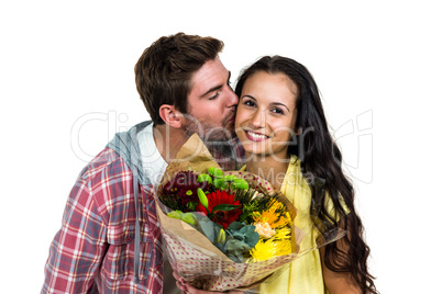Smiling woman holding bouquet and being kissed by boyfriend