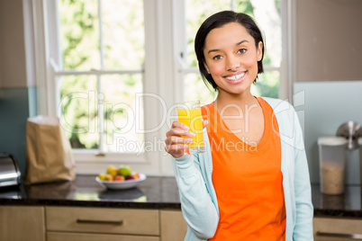 Smiling brunette holding glass of orange juice