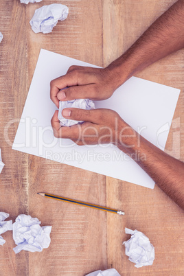 Businessman by notepad making paper balls at desk