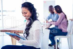 Young businesswoman using tablet PC with colleagues in backgroun