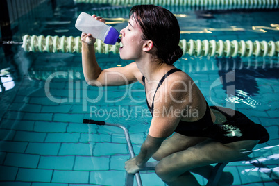 Woman cycling in the pool while drinking water