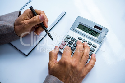 Businessman using calculator and taking notes