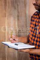 Businessman with smartphone writing on book