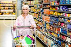 Smiling senior woman pushing trolley