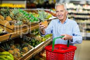 Smiling senior man picking pineapple