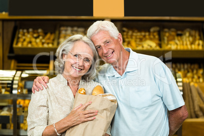 Smiling senior couple holding bakery bag