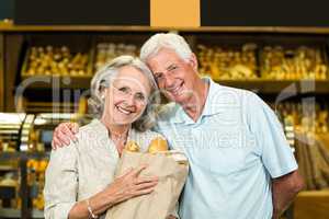 Smiling senior couple holding bakery bag