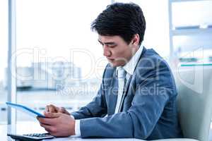 Concentrated asian businessman using his tablet