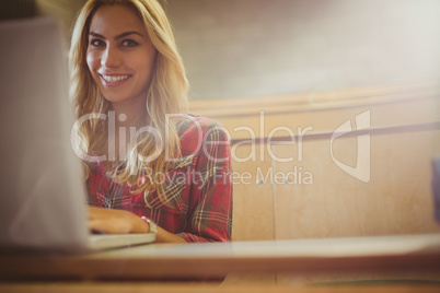 Smiling female student using laptop