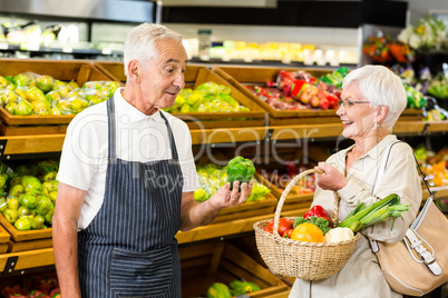 Senior customer and worker discussing vegetables