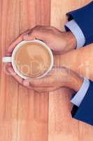 Cropped hands of businessman holding coffee cup on desk