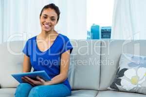 Smiling woman using tablet on sofa