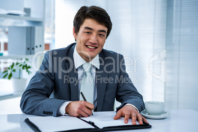 Smiling asian businessman sign a contract