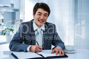 Smiling asian businessman sign a contract