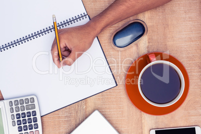 High angle view of businessman writing on notebook by coffee