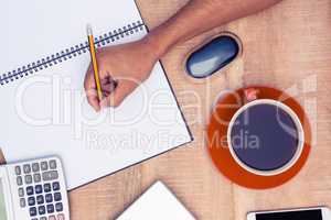 High angle view of businessman writing on notebook by coffee