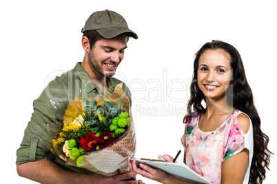Woman signing for bouquet delivery with smiling postman