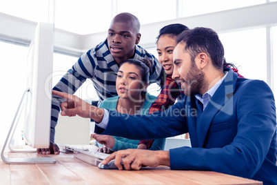 Businessman explaining colleagues over computer