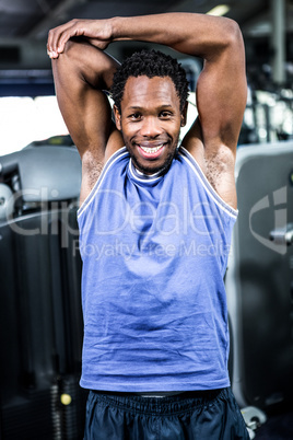 Smiling muscular man stretching arms
