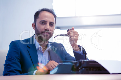 Portrait of hipster businessman working on typewriter