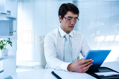 Serious asian businessman using his tablet