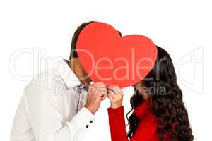 Couple covering faces with paper heart