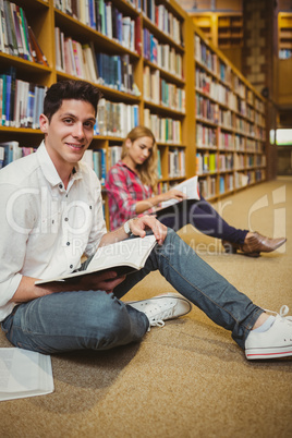 Smiling male student revising on floor