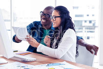 Cheerful businessman discussing with businesswoman over document