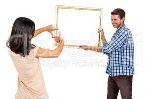 Happy young couple hanging picture frame