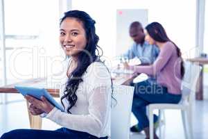 Portrait of young businesswoman holding tablet PC with colleague