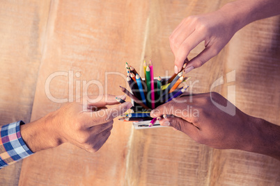 Business people choosing pencils from container