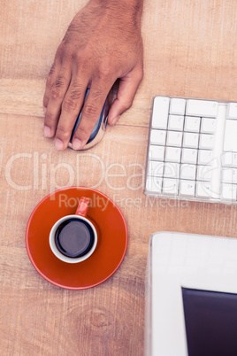 Businessman using mouse by coffee cup while working at desk