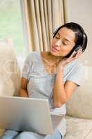 Smiling brunette using laptop and headphones