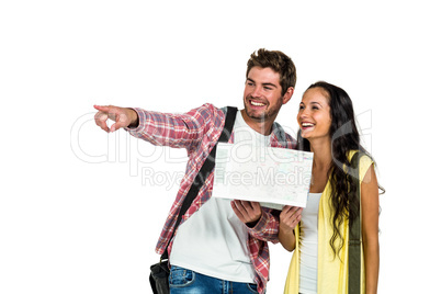 Smiling couple holding map while pointing somewhere