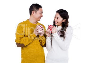 Happy young couple looking at each other while holding cups