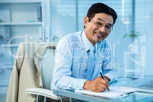 Smiling asian businessman writing a report