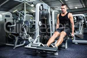 Muscular man using exercise machine for legs