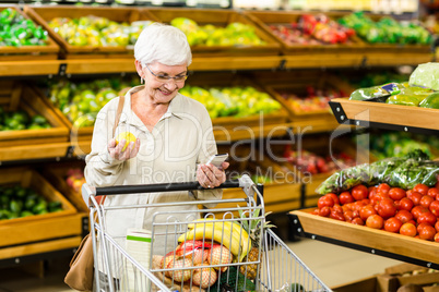 Senior woman holding phone and an apple